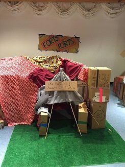 A fort that is made with sticks, cardboard boxes, and blankets