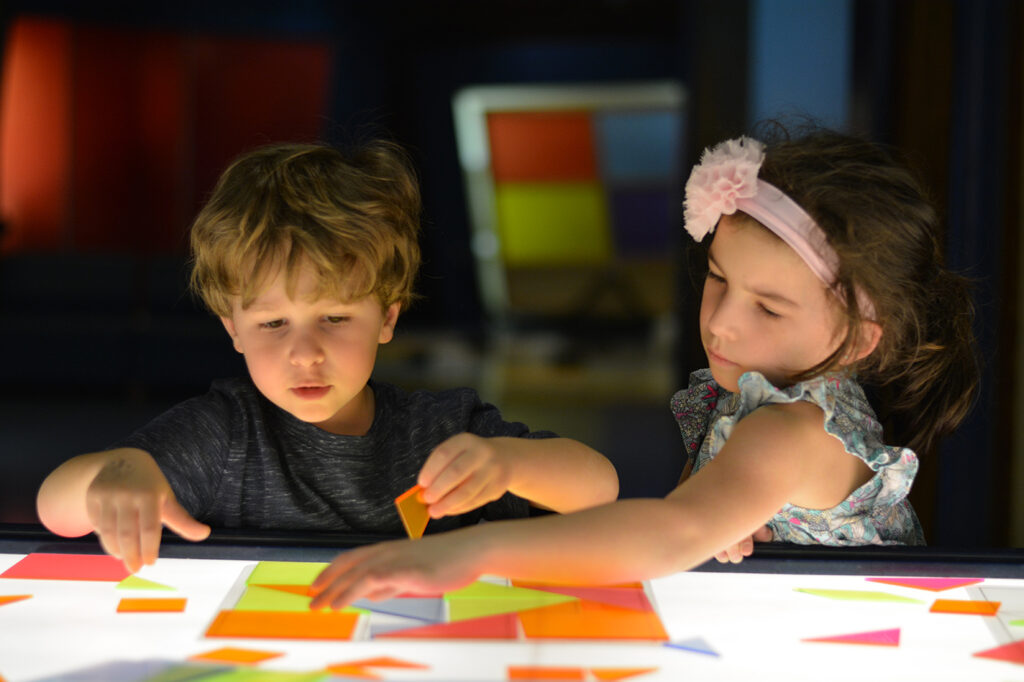 Two kids playing with tangram table