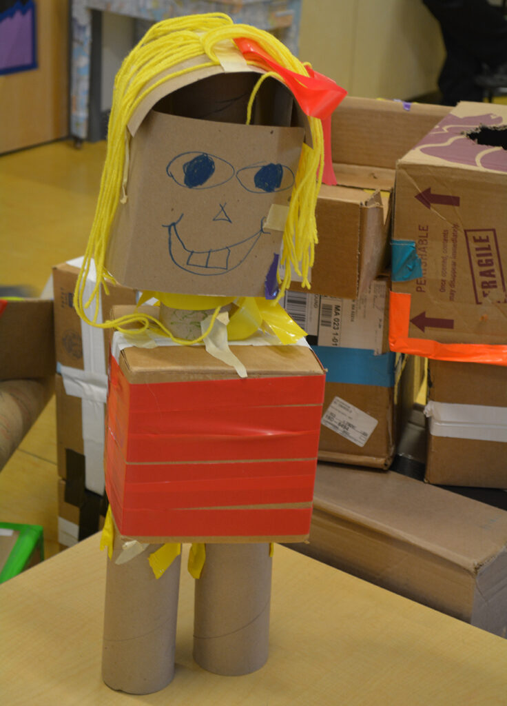 Child's creation of a person using cardboard, tape, and string
