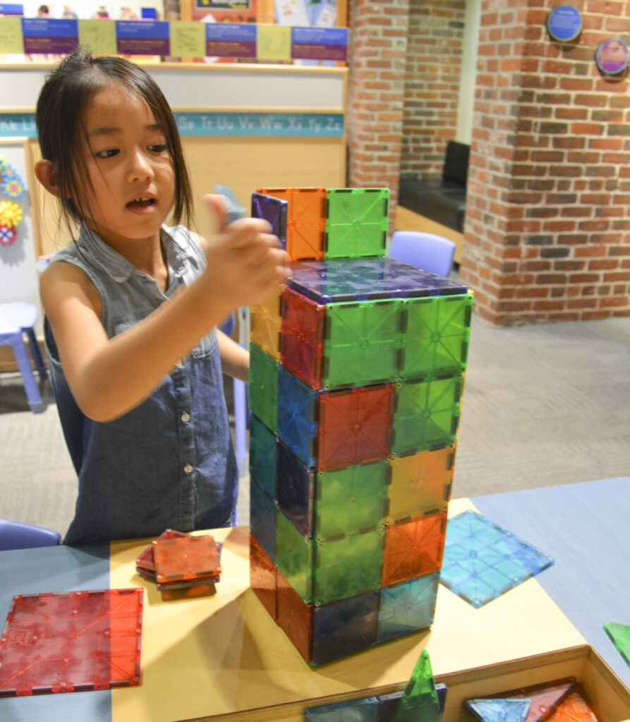 Girl builds a structure using many colorful squares